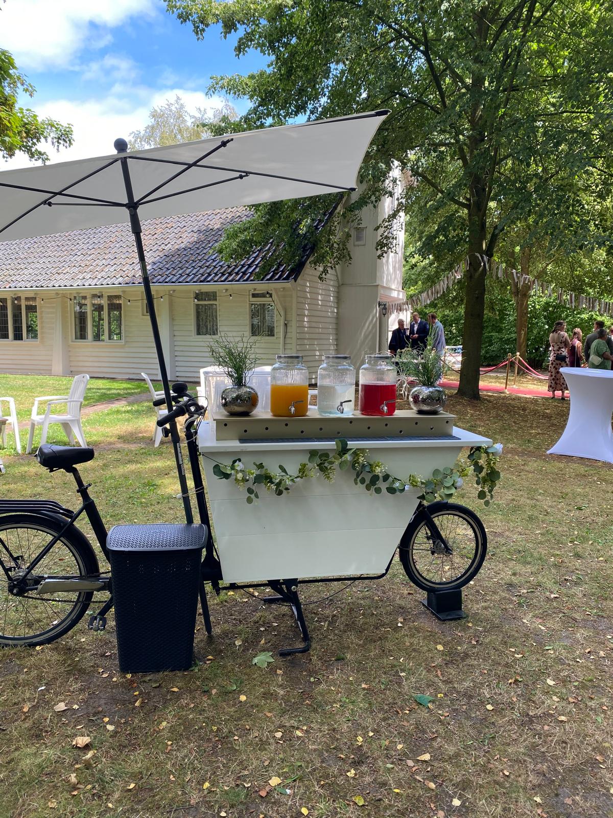 Crèmekleurige bakfiets met glazen tapkannen limonade en eucalyptus decoratie tijdens de borrel